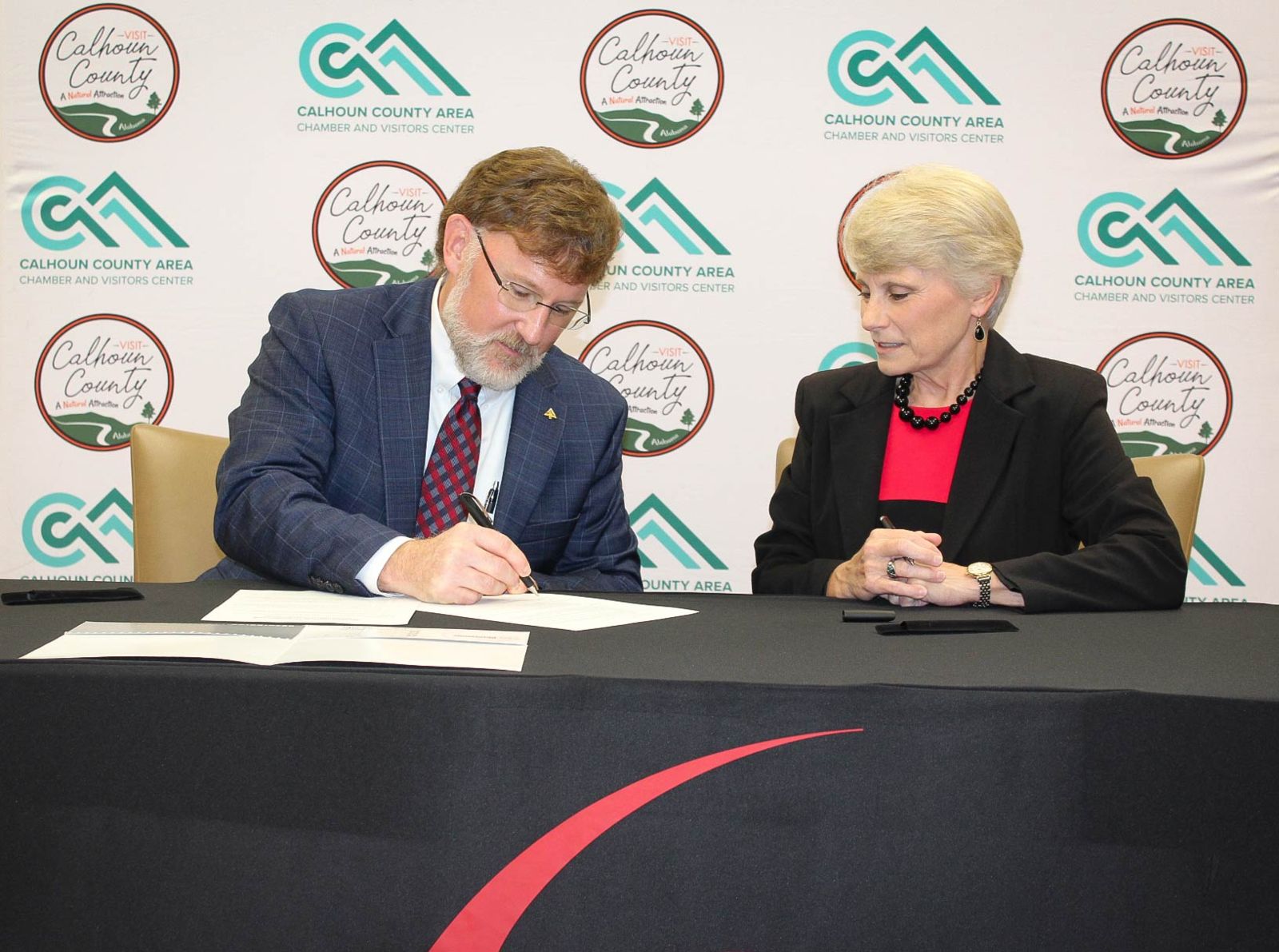 Dr. Kathy Murphy, right, president of Gadsden State, looks on as Corey McWhorter, president of the Calhoun County Chamber of Commerce Board of Directors, signs the MOU for the BOGO Scholarship